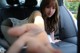 A woman sitting in the back seat of a car holding a remote control.