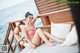 A woman in a pink bathing suit sitting on a bed.