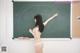 A woman in a white bikini standing in front of a blackboard.