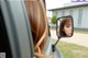 A woman is looking in the rear view mirror of a car.