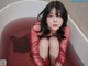 A woman sitting in a bathtub filled with red liquid.